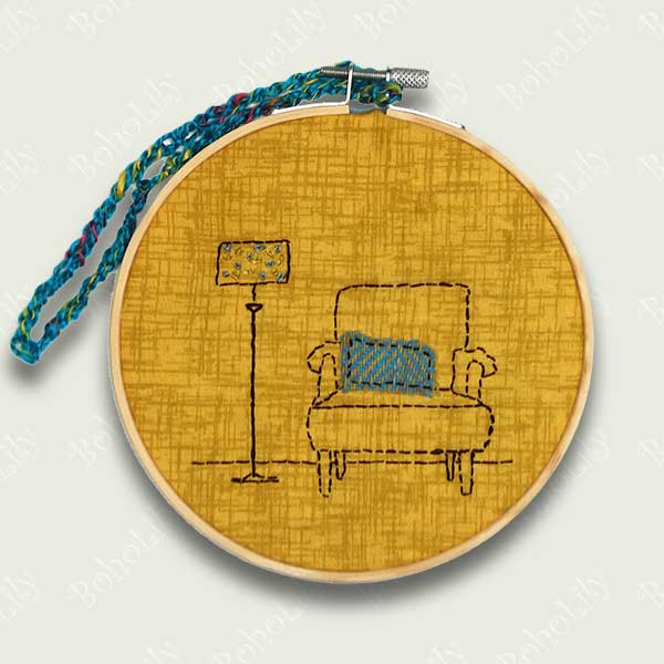 This is a one-off design in my ‘interiors’ collection. Designed and hand stitched by me using DMC threads onto a mustard background with a Harris tweed cushion on the armchair. The back of the hoop is covered in a blue wool felt and is ready to hang using the contrasting teal crocheted loop.  Only one available.