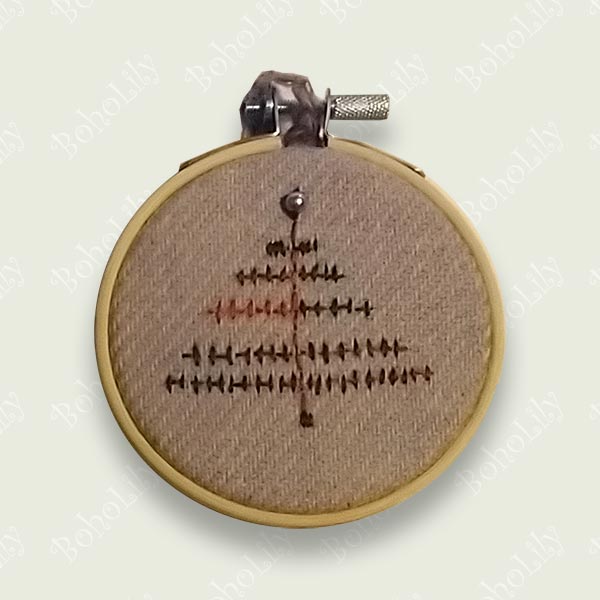 A modern Christmas tree stitched with variegated thread onto a lavender Harris tweed fabric, topped with a little pearl bead. Supplied with a crocheted yarn loop in a contrasting colour.