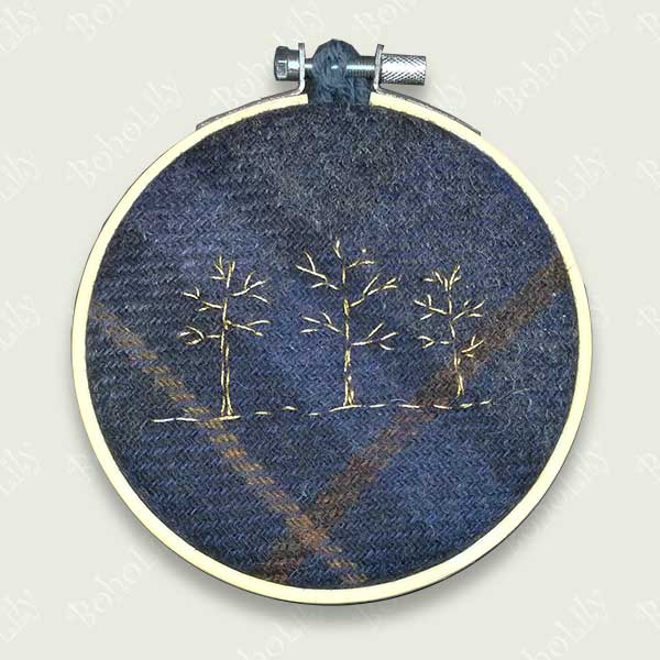 One of the ‘Tweed’ collection. Three winter trees stitched in gold metallic thread on to dark blue Harris tweed tartan. Supplied with contrasting crocheted loop made with 100% British Wool. One available.