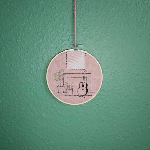 This is a one-off design in my ‘interiors’ collection. Designed  and hand stitched by me using DMC threads onto a subtle pink background with an applique ‘picture’ over the fireplace. The back of the hoop is covered in pale pink wool felt and is ready to hang using the contrasting cotton yarn crocheted  loop. Only one available.